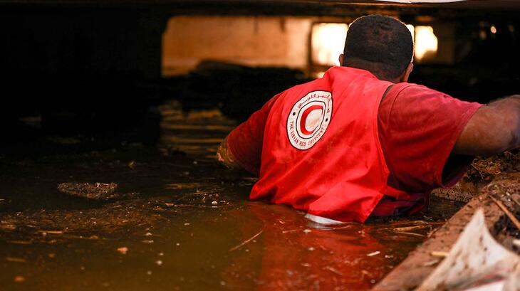 A Libyan Red Crescent volunteer crosses flood water in search of survivors from the devastating floods that hit Libya in September 2023.