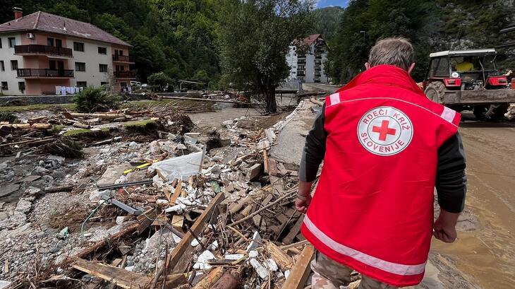 Un volontaire de la Croix-Rouge slovène évalue les dégâts causés par de graves inondations en Slovénie en août 2023, alors que son équipe et lui apportent une aide aux communautés touchées.