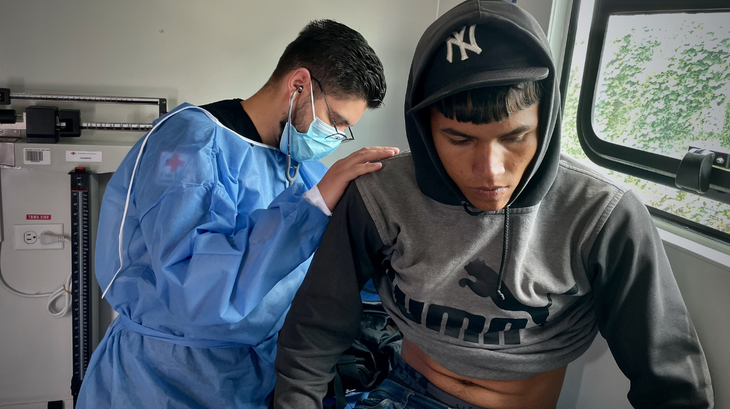 يتلقى يندر مساعدة طبية من أحد متطوعي الصليب الأحمر الإكوادوري. 