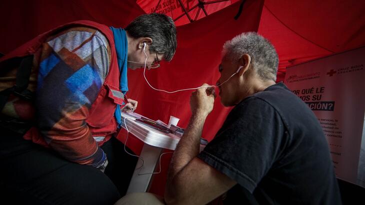 A member of an Argentine Red Cross HSP team helps a migrant get in touch with family.