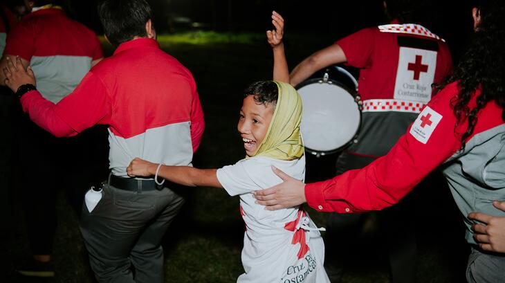 A young Costa Rican Red Cross volunteer smiles as he rides in a 'human train' through the campsite at the National Youth Camp in January 2025. 
