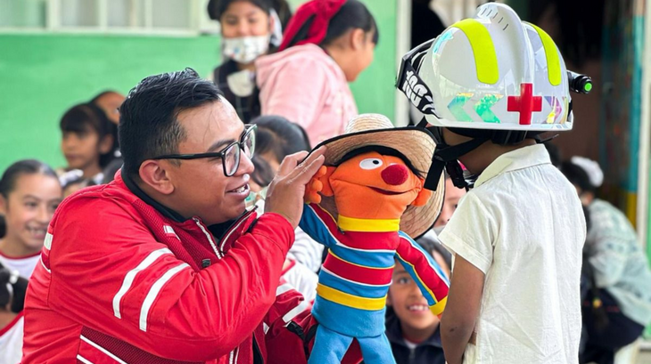 A Mexican Red Cross volunteer shares a playful moment with a child using a puppet.